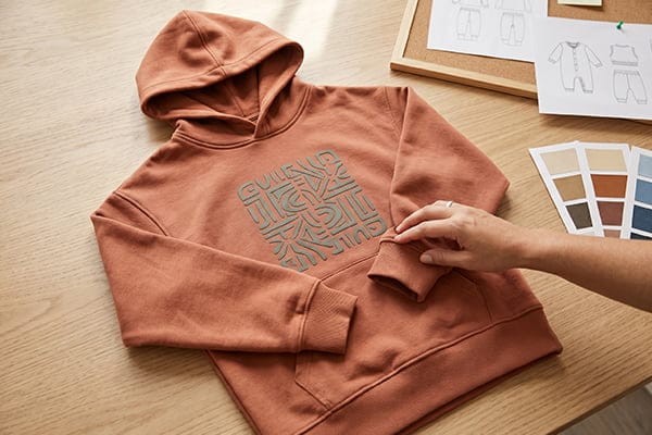 A child wearing an oversized hoodie with a puff print graphic